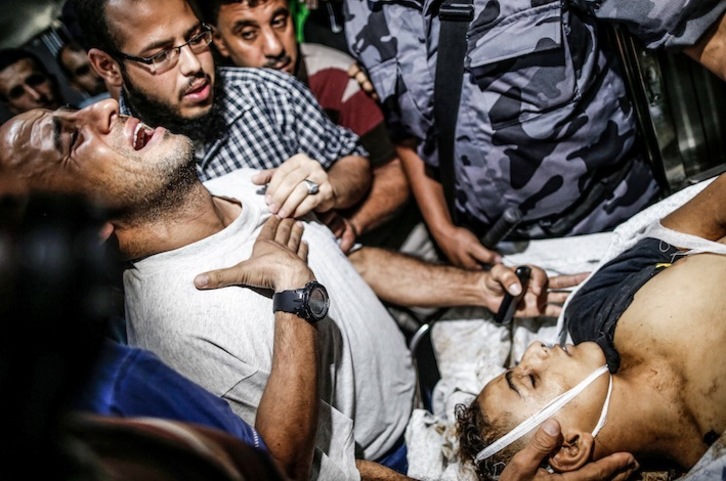 El padre de uno de los jóvenes palestinos muertos por soldados israelíes llora junto al cadáver de su hijo. (Mahmud HAMS/AFP)