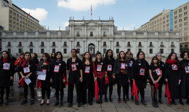 Activistas de derechos humanos muestran retratos de desaparecidos durante la dictadura ante La Moneda. (Martín BERNETTI / AFP)