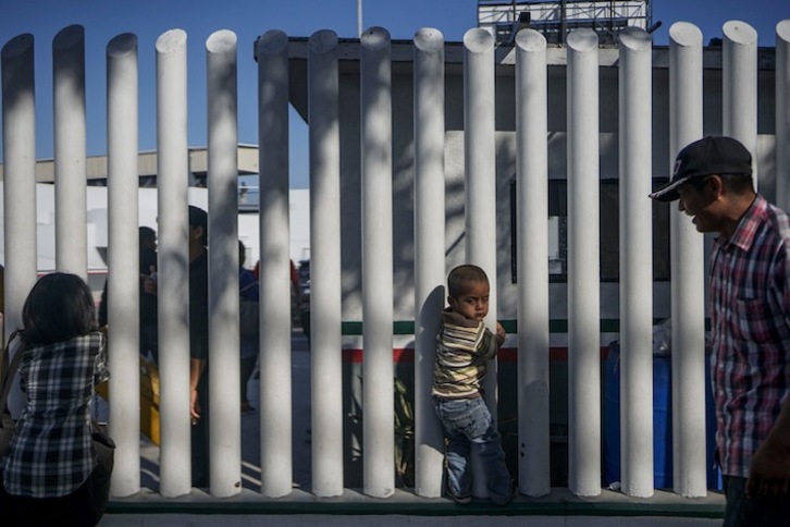 Un niño hondureño, en la valla fronteriza de Tijuana. (Sandy HUFFAKER / AFP)