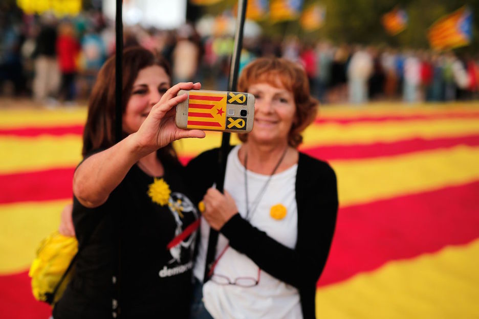 Dos mujeres se hacen un selfie mientras aguardan a que comience en lacto «Llum y llibertat» en El Bruc. (Pau BARRENA/AFP)