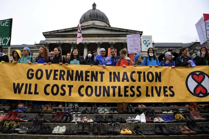 Sendagileak protestan Londreseko Trafalgar Square plazan, kutsadurak eragindako hildakoak gogoratzen dituzten oinetakoak aurrean dituztela. (Daniel LEAL-OLIVAS | AFP)