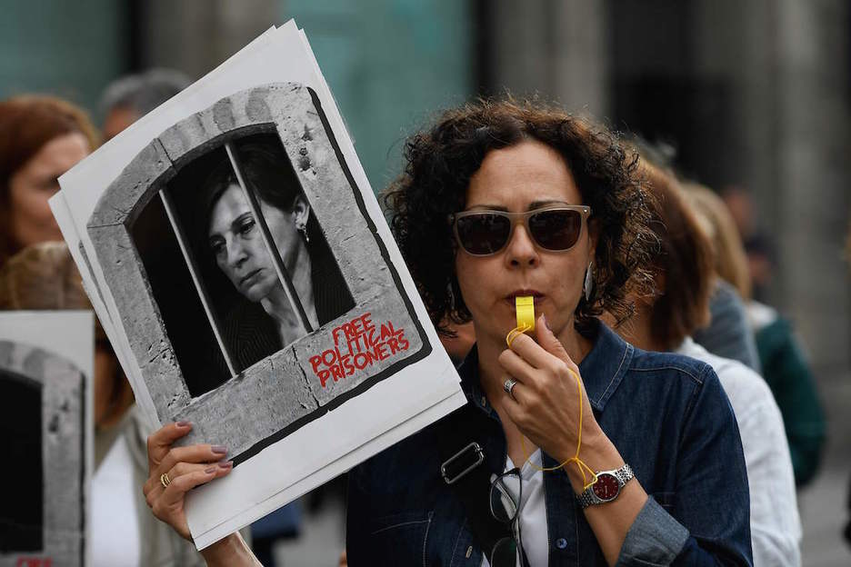 Una mujer hace sonar un silbato mientras porta una imagen de Carmen Forcadell encarcelada. (Lluís GENÉ/AFP)