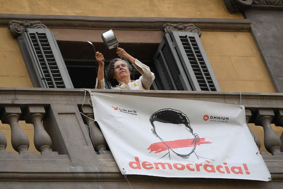 Una mujer golpea una cacerola en el balcón de su casa, en Barcelona. (Lluís GENÉ/AFP)