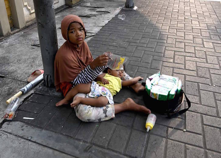 Una madre junto a su bebé vende pañuelos en las calles de Jakarta. (Go CHAI HIN/AFP)