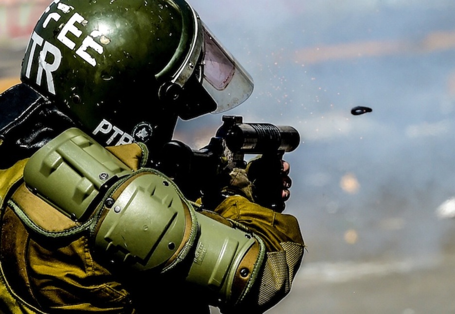 Un policía dispara entre gases lacrimógenos, en Santiago. (Martin VERNETTI | AFP)