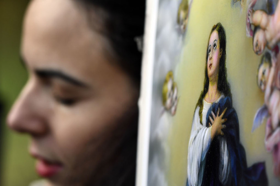 Una mujer reza junto al acceso al Valle de los Caídos. (Oscar DEL POZO / AFP)