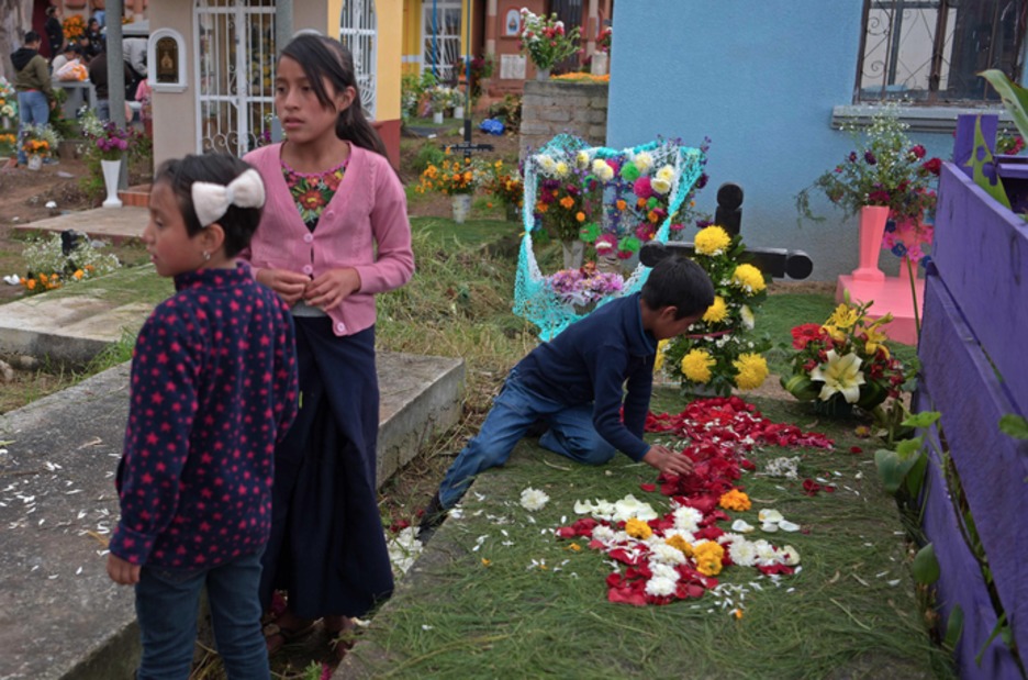Un niño juega en la tumba de un ser querido junto a sus hermanas. (Agustin PAULLIER / AFP)