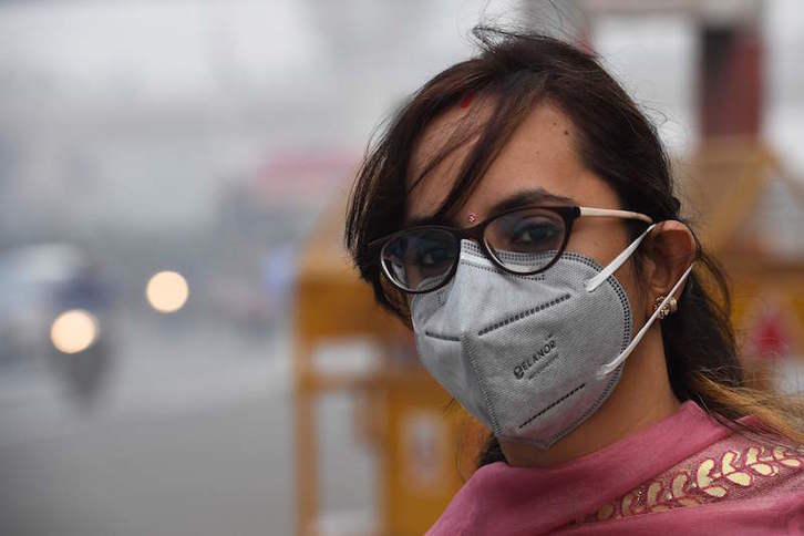 Una  mujer se protege de la alta contaminación en Nueva Delhi con una mascarilla.  (Prakash SINGH/AFP)