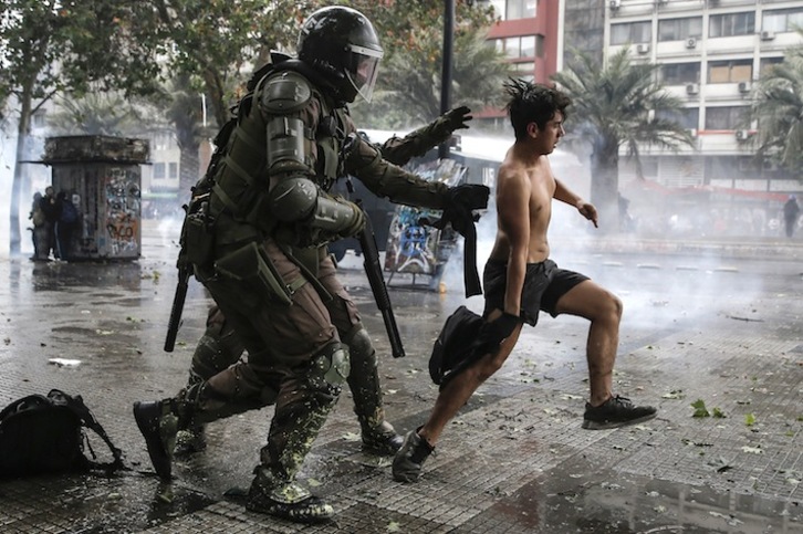 Dos policías antidisturbios tratan de detener a un joven manifestante. (Javier TORRES/AFP)