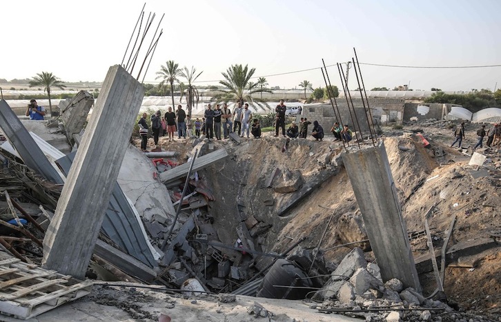 Palestinar talde bat, Israelgo Armadaren aire-erasoen ondorioz txikitutako etxe baten inguruan. (Said KHATIB/AFP)