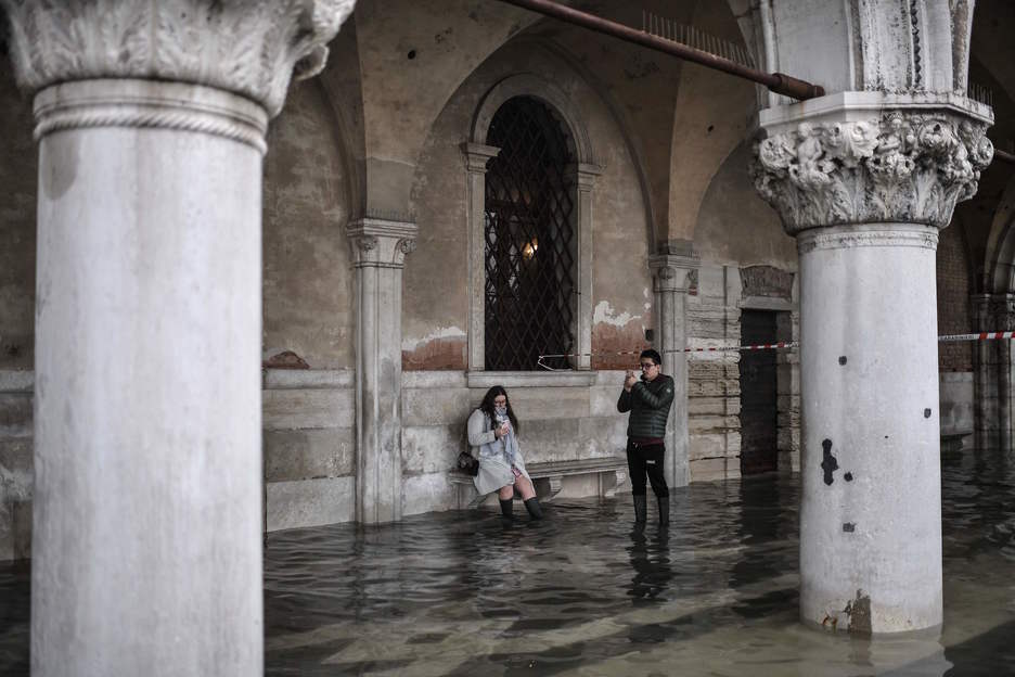 Los turistas, que han tenido que calzarse botas de agua, no se han resistido a inmortalizar la excepcional inundación. (Marco BERTORELLO/AFP)