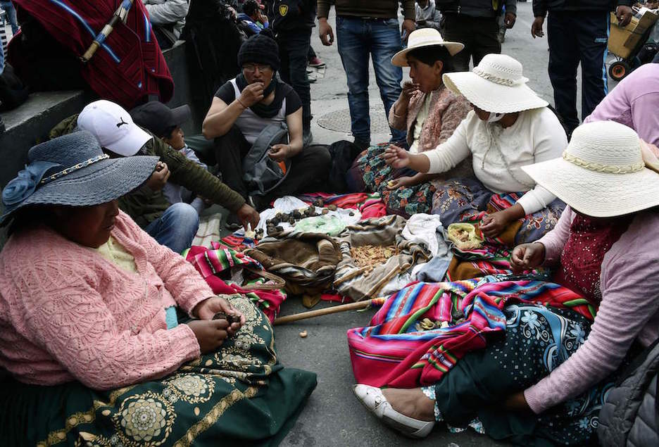 Un grupo de indígenas aymaras hacen un descanso para comer. (Aizar RALDES/AFP)