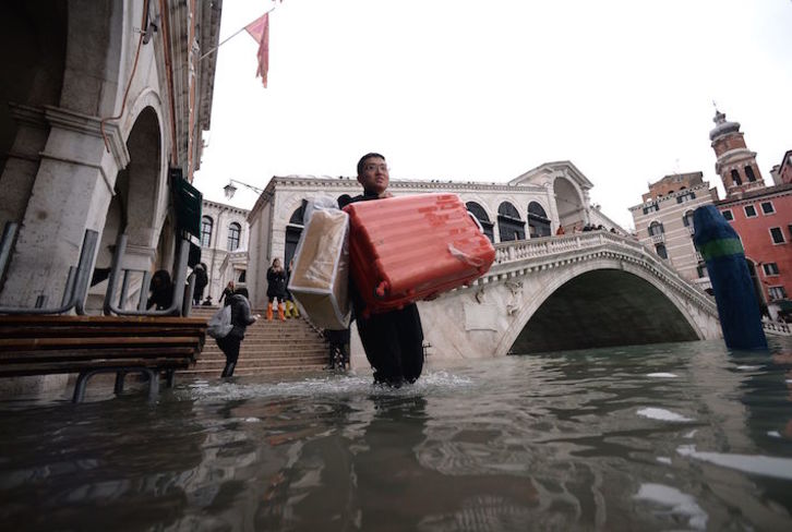 Un turista carga sus maletas por las calles de una Venecia anegada. (Filippo MONTEFORTE/AFP)