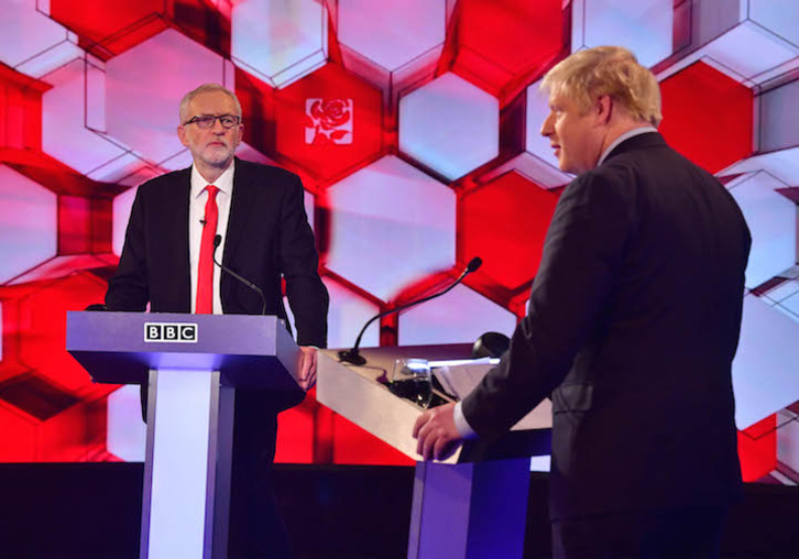 Corbyn observa a Johnson mientras este se dirige a los televidentes. (JEFF OVERS / AFP)