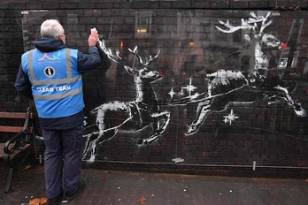 Un operario limpia el plástico colocado para proteger el mural. (PAUL ELLIS / AFP)