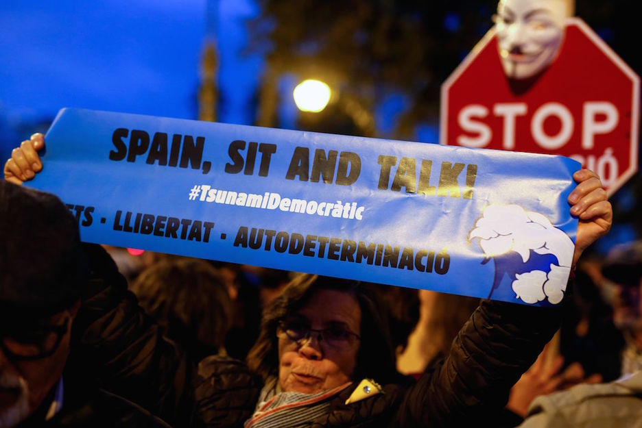 Una mujer con una cartulina azul con el lema «Spain, sit and talk». (Pau BARRENA/AFP)