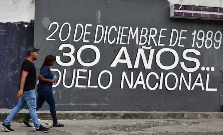 Una pareja camina en El Chorrillo ante un mural que recuerda la invasión de 1989. (Luis ACOSTA / AFP) 