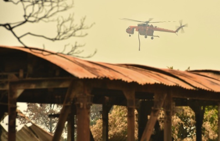 Un helicóptero sobrevuela sobre los restos de un café destruido por los incendios forestales en la ciudad de Bilpin, a 70 kilómetros de Sydney. (Peter PARKS/FOKU)