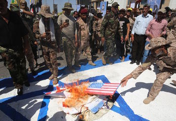 Milicianos de Kataeb Hizbulah queman una bandera estadounidense en Bagdad. (Ahmad AL-RUBAYE)