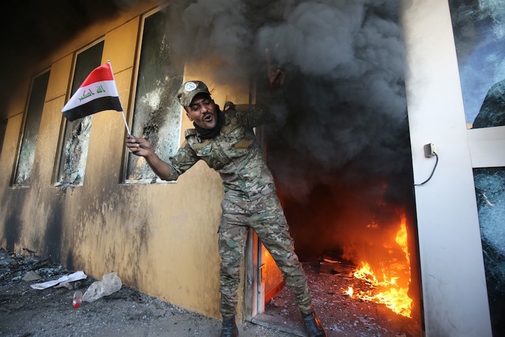 Un manifestante muestra una bandera iraquí tras lograr entrar en un edificio de la Embajada. (Ahmed AL–RUBAYE | AFP)
