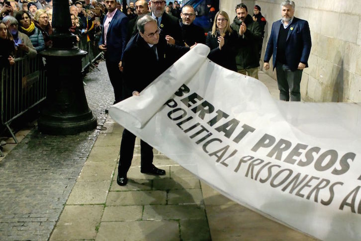 Torra despliega la pancarta por la libertad de los presos políticos que estaba en un balcón del Palau. (Pau BARRENA/AFP)