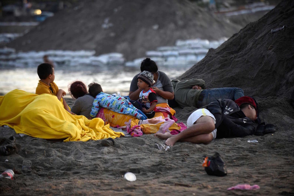 Una familia despierta tras pasar la noche en la orilla mexicana del río Suichate, en Ciudad Hidalgo. (Johan ORDOÑEZ/AFP)