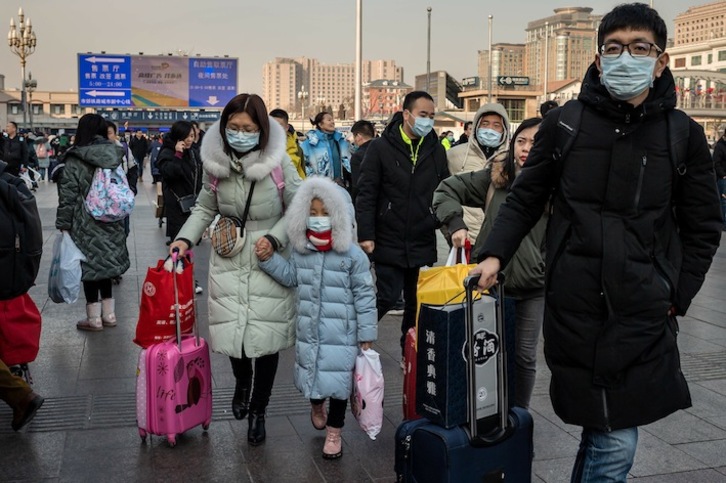 Cuidadanos chinos se protegen con mascarillas cerca de la estación de tren de Pekin. (Nicolas ASFOURI / AFP)
