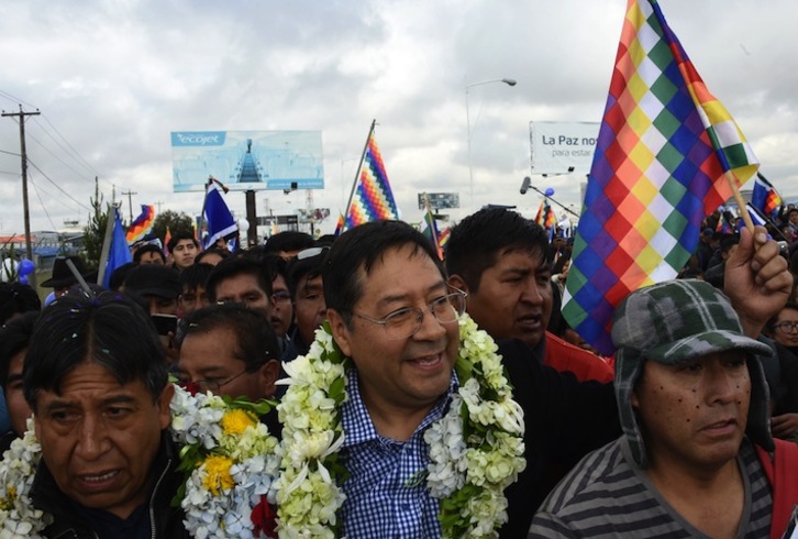 David Choquehuanca (i) recibe, junto a decenas de seguidores, a Luis Arce (c) en el aeropuerto de El Alto. (Aizar RALDES/AFP)