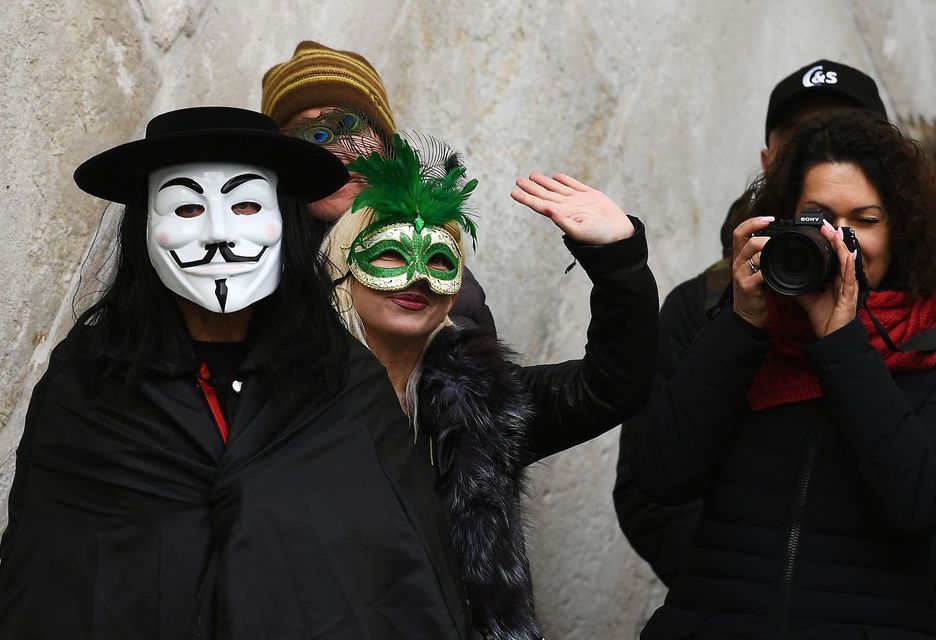 Juerguistas enmascarados y turistas toman fotos durante la regata tradicional (Vicenzo PINTO/AFP)