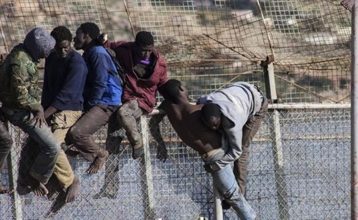 Personas migrantes subidas a la valla de Melilla, en una imagen de archivo. (AFP)