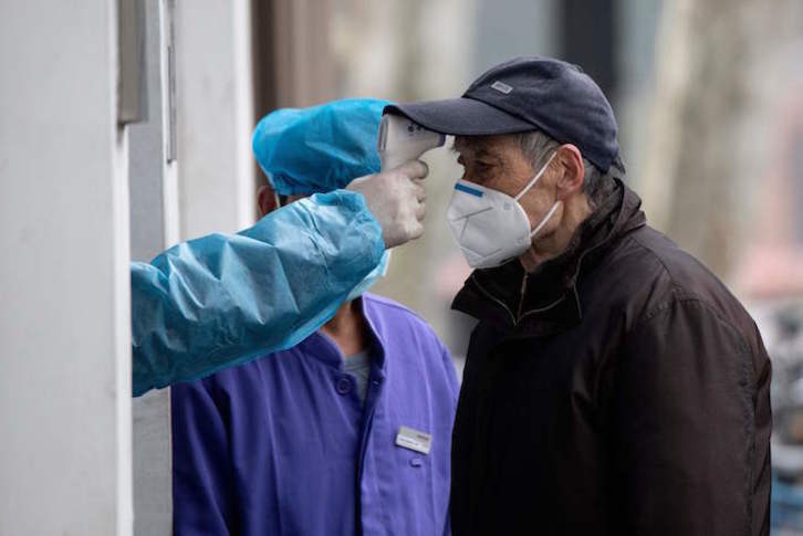 Un trabajador sanitario toma la temperatura a un hombre en la entrada de un hospital de Shanghai. (Noel CELIS/AFP)