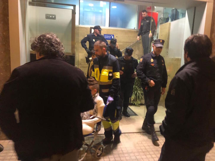 La joven herida, en silla de ruedas y rodeada de policías.