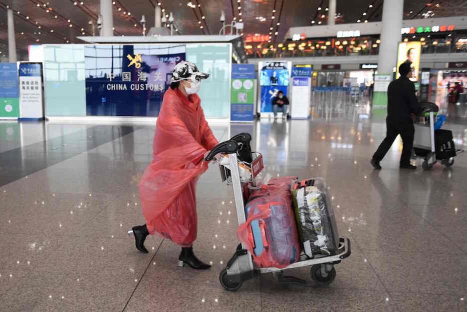 Una mujer envuelta en plástico, al igual que su equipaje, en el aeropuerto de Pekín. (GREG BAKER / AFP)