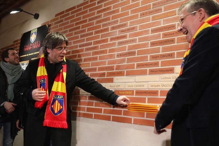 Puigdemont descubre una placa con su nombre en la Piedra del Muro de las Leyendas de la USAP junto al presidente de ese club de rugby, François Rivière. (Raymond ROIG/AFP)