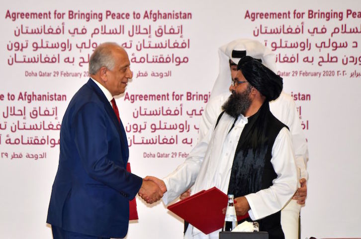 El representante de EEUU, Zalmay Khalilzad, y el líder talibán, mulá Abdul Ghani Baradar, se dan la mano tras la firma del acuerdo en Doha. (Giuseppe CACACE/AFP)