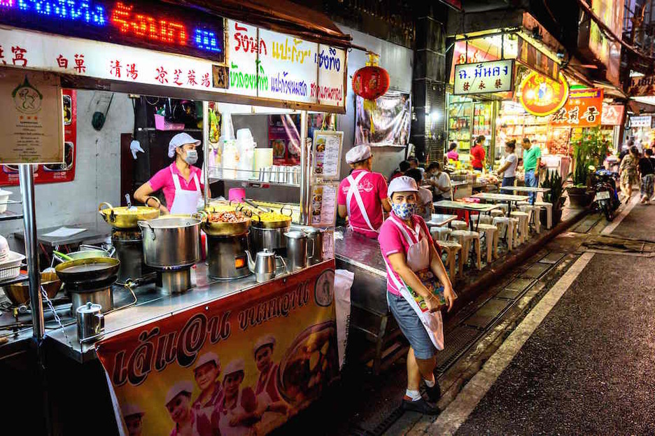 Vendedores de puestos de comida callejeros aguardan clientes en Yaowarat Road, la calle principal de Chinatown en Bangkok. (Mladen ANTONOV/AFP)