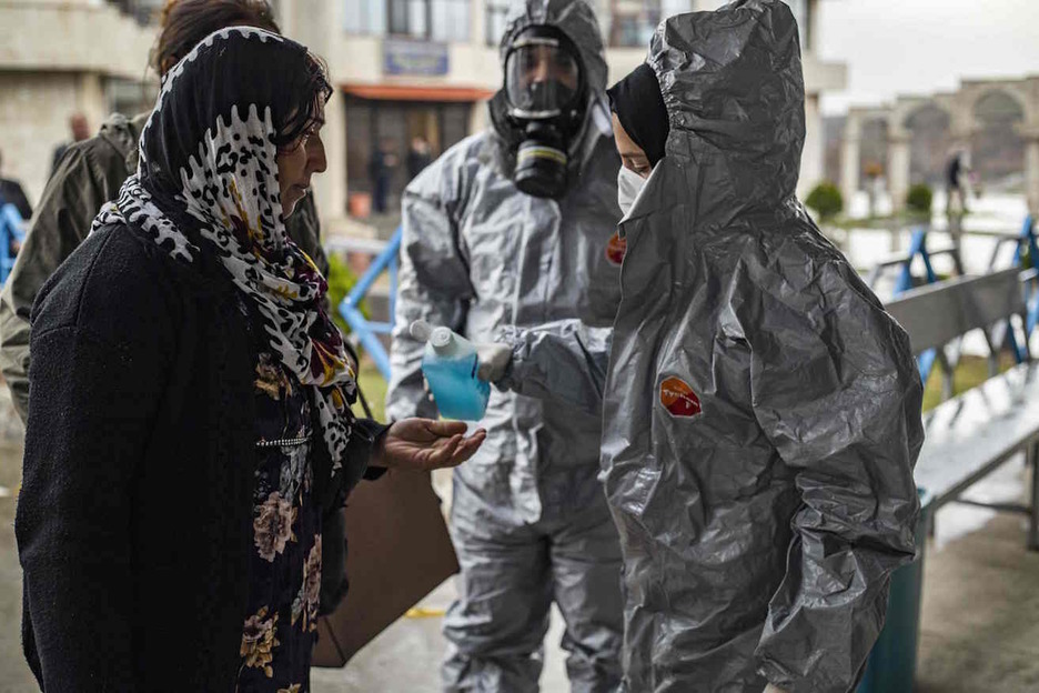 Un médico desinfecta las manos de una pasajera kurda a su llegada a Siria. (Delil SOULEIMAN/AFP) Un médico desinfecta las manos de una pasajera kurda a su llegada a Siria. (Delil SOULEIMAN/AFP)
