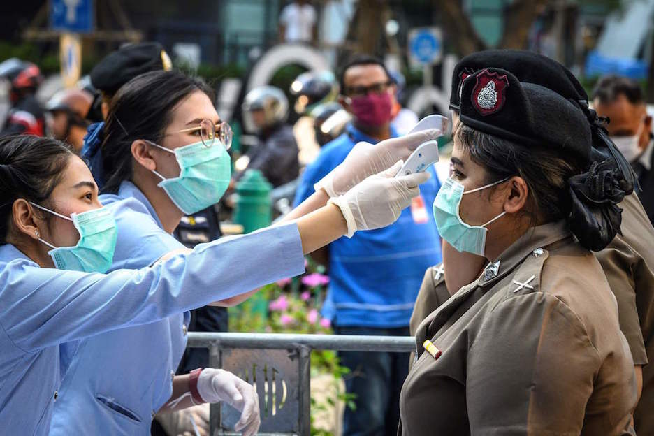 Personal sanitario toma la temperatura a unas policías en Bangkok. (Mladen ANTONOV/AFP)