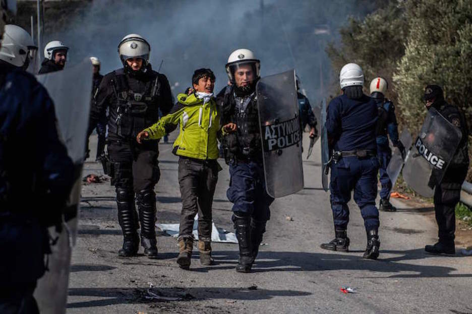 Policías griegos detienen a un joven migrante cerca de Moria, en la isla de Lesbos. (Angelos TZORTZINIS/AFP) 