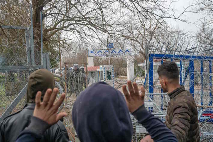 Migrantes frente a policías griegos, en la zona fronteriza con Turquía. (Bulent KILIC/AFP)