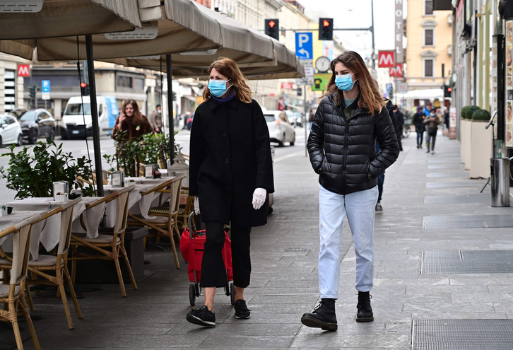 Dos personas con mascarillas por la calle en Italia. (Miguel MEDINA / AFP).