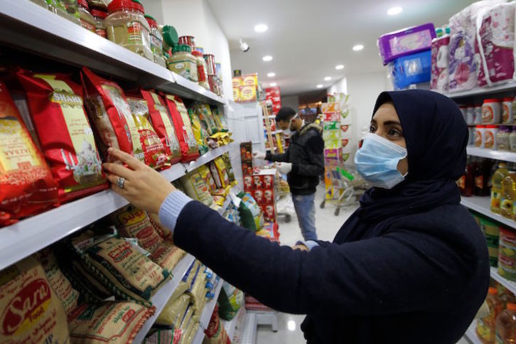Una mujer palestina compra en un supermercado de Gaza con mascarilla. (Mohammed Abed/AFP)
