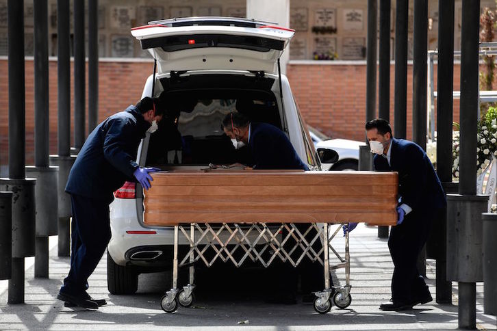 Operarios con mascarilla llevan un féretro a un cementerio de Madrid, este martes. (Oscar DEL POZO | AFP)