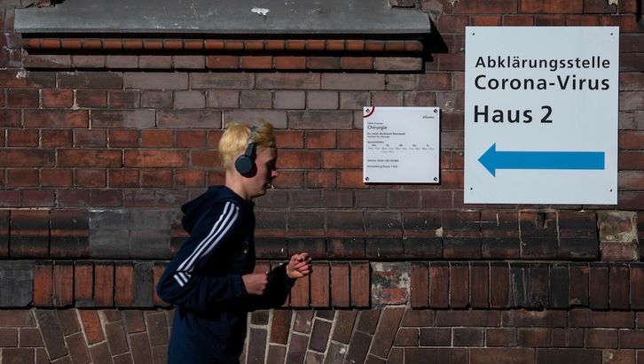 Un joven pasa ante un cartel que dirige a la gente a uno de los centros habilitados en Berlín para realizar test de coronavirus. (John MACDOUGALL/AFP)