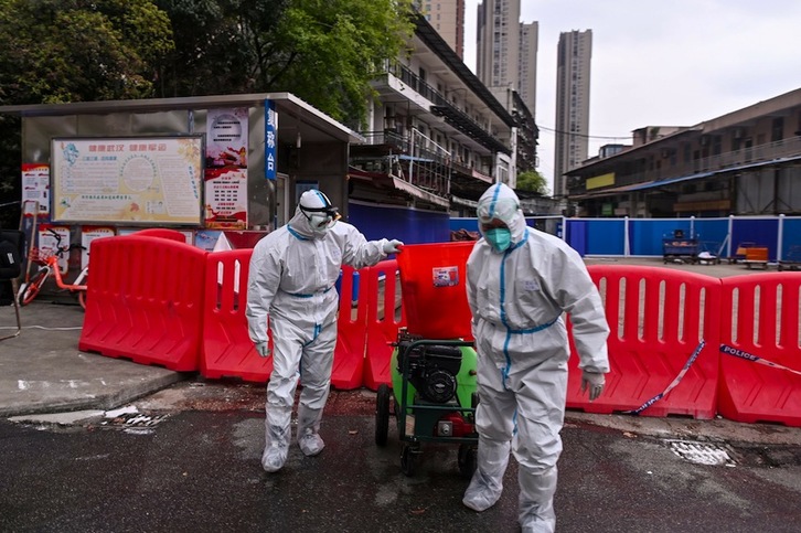 Trabajadores con buzos de protección desinfectan, este lunes, la zona próxima al mercado de Huanan, en la ciudad de Wuhan. (Hector RETAMAL | AFP)