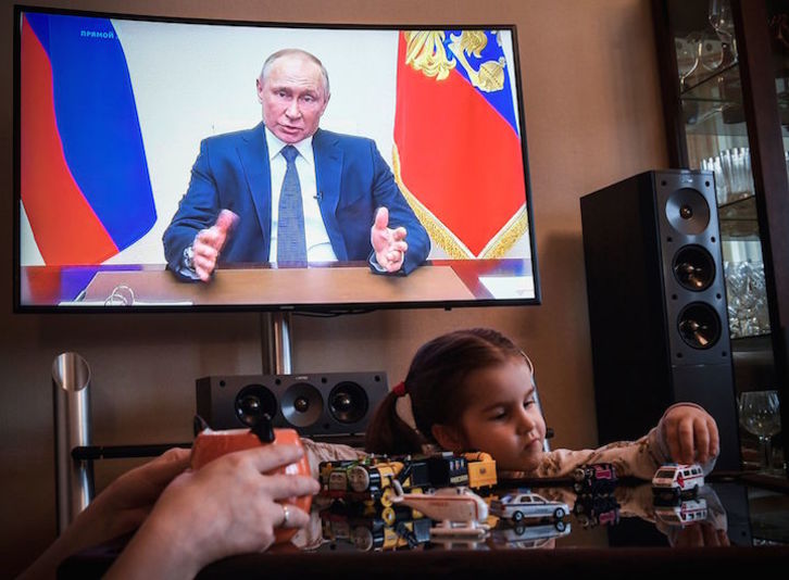 El presidente ruso, Vladimir Putin, durante su discurso, en el televisor de un hogar de Moscú. (Alexander NEMENOV/AFP)