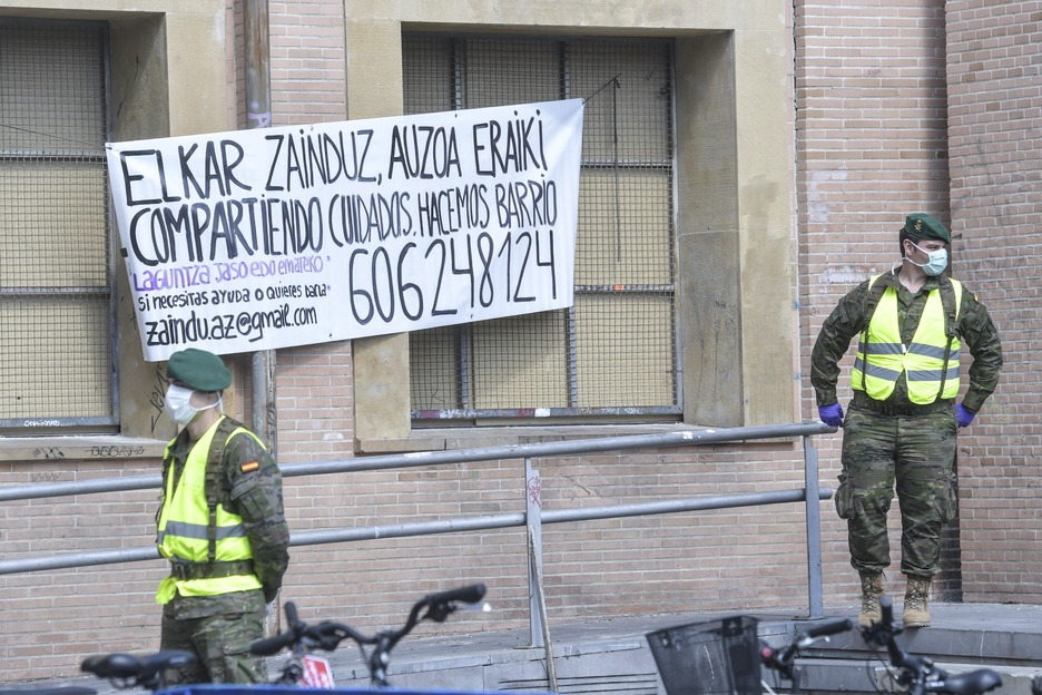 Militares españoles frente a un cartel que informa sobre la red de cuidados de Alde Zaharra. 
