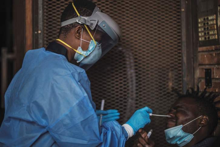 Un sanitario del Departamento de Salud de Gauteng toma muestras de un hombre durante una prueba de detección de coronavirus en Johannesburgo, Sudáfrica. (Marco LONGARI/AFP)