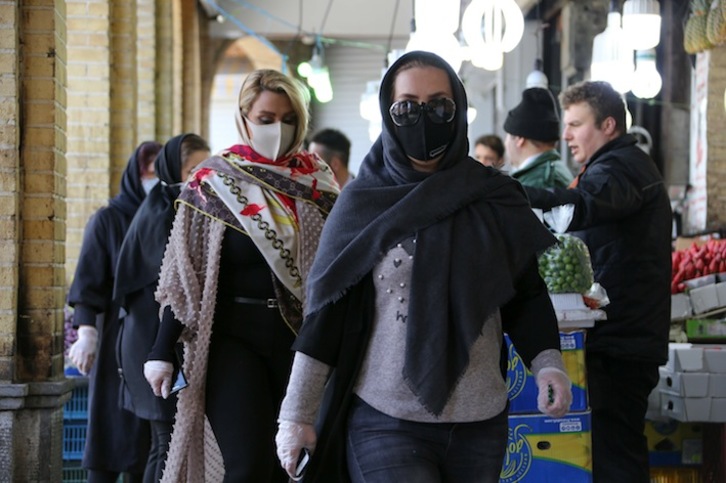 Las mujeres acuden con mascarillas y guantes a un mercado en Irán. (Atta KENARE/AFP)
