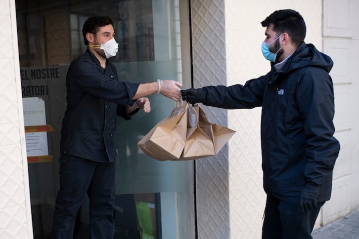 Repartidor entregando el pedido en Barcelona, con la mascarilla puesta. (Josep LAGO/AFP)